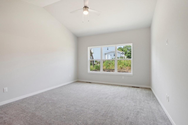 empty room featuring vaulted ceiling, light colored carpet, and ceiling fan