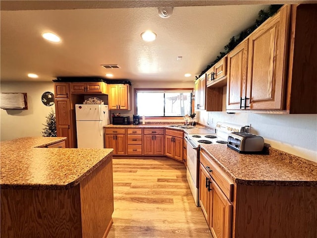 kitchen featuring light stone counters, light hardwood / wood-style floors, sink, and white appliances