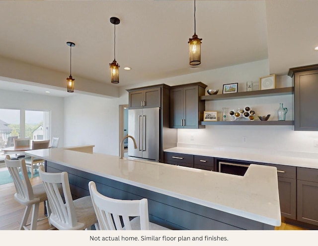 kitchen with a kitchen breakfast bar, high end refrigerator, light hardwood / wood-style flooring, and decorative light fixtures