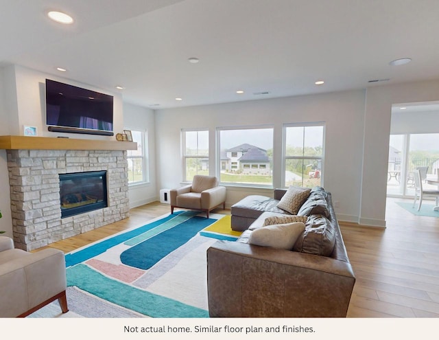 living room with a stone fireplace and light wood-type flooring