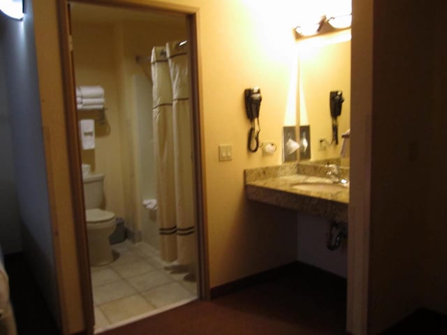 bathroom with tile patterned flooring, a shower with curtain, toilet, and sink