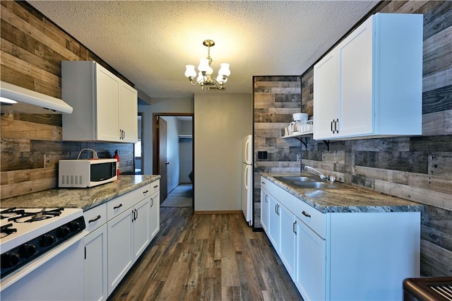 kitchen with white appliances, white cabinets, dark hardwood / wood-style floors, and wooden walls