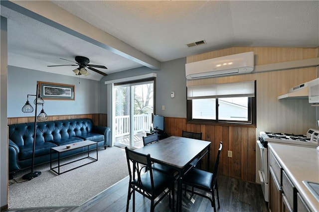 carpeted dining area featuring ceiling fan, vaulted ceiling with beams, and a wall mounted AC