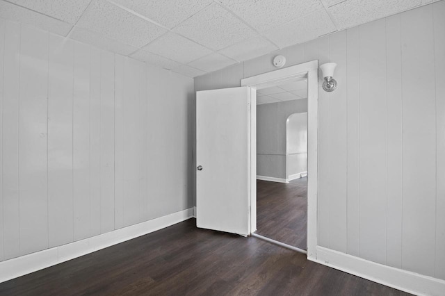 empty room with dark hardwood / wood-style floors and a paneled ceiling