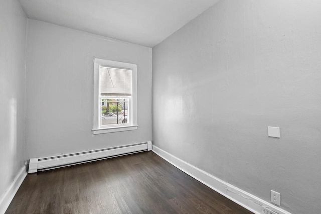 spare room with a baseboard radiator and dark hardwood / wood-style floors