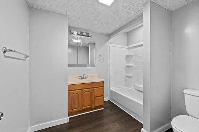 full bathroom featuring shower / washtub combination, toilet, a drop ceiling, wood-type flooring, and vanity