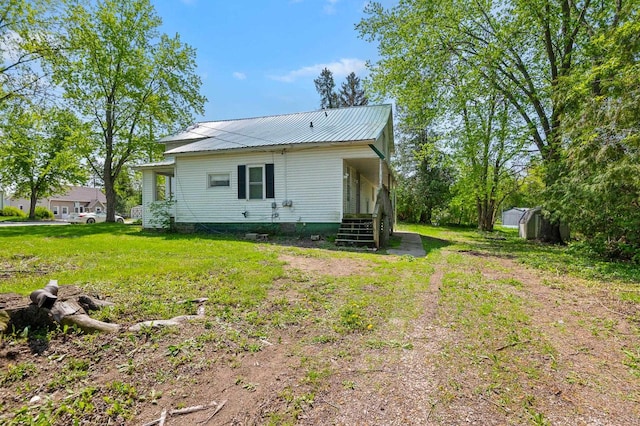 rear view of house featuring a yard and a shed