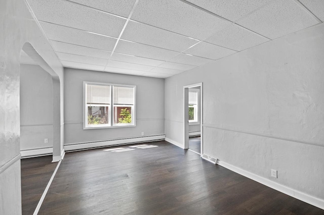 unfurnished room featuring dark wood-type flooring, a baseboard radiator, and a drop ceiling