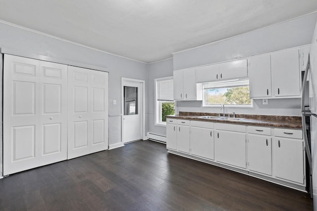 kitchen with dark hardwood / wood-style floors, stainless steel fridge, a baseboard heating unit, sink, and white cabinets