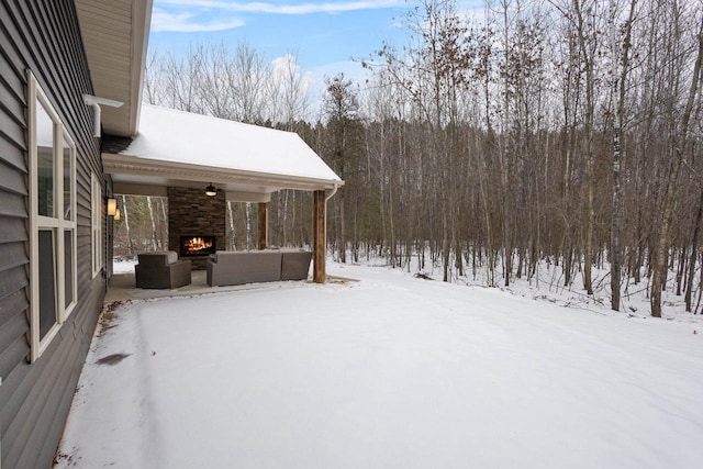 yard covered in snow with an outdoor living space with a fireplace and ceiling fan