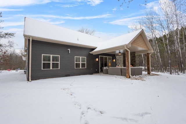 snow covered rear of property featuring an outdoor living space and ceiling fan