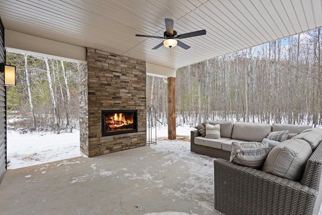 snow covered patio with an outdoor living space with a fireplace and ceiling fan