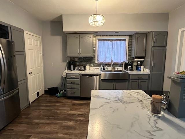 kitchen with stainless steel appliances, pendant lighting, dark wood-type flooring, gray cabinetry, and sink