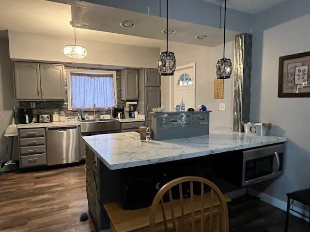 kitchen with hanging light fixtures, appliances with stainless steel finishes, dark hardwood / wood-style floors, and gray cabinets