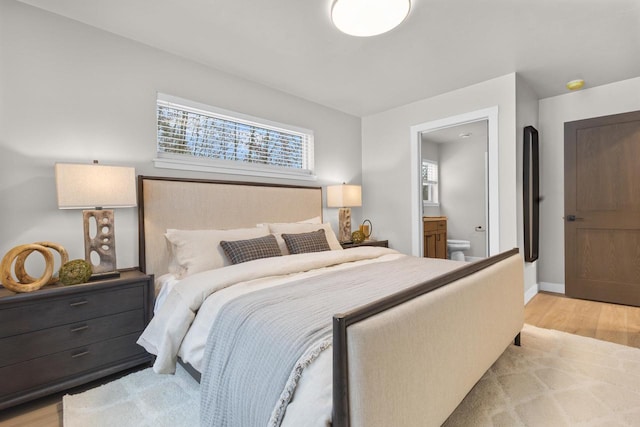 bedroom with ensuite bath and light hardwood / wood-style flooring