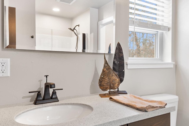 bathroom with a shower, vanity, and toilet