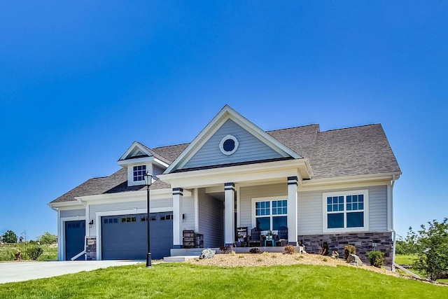 view of front of property with a garage, a front lawn, and a porch