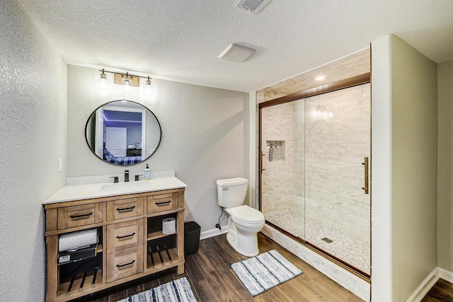 bathroom with a textured ceiling, a shower with door, hardwood / wood-style floors, and toilet