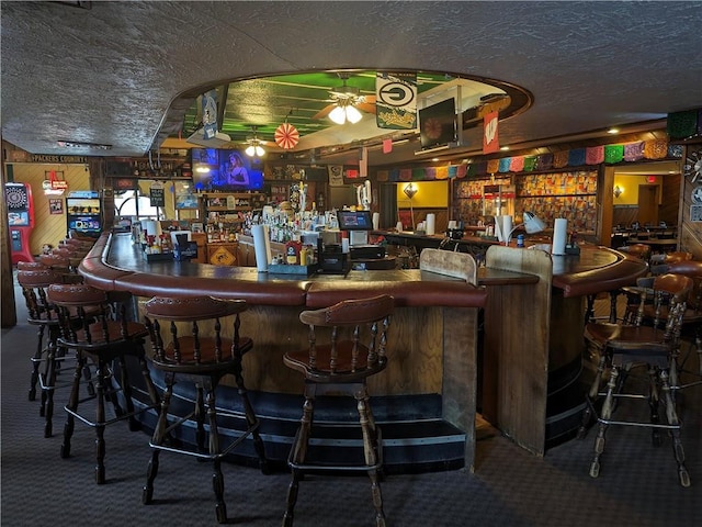 bar with a textured ceiling, carpet, and ceiling fan