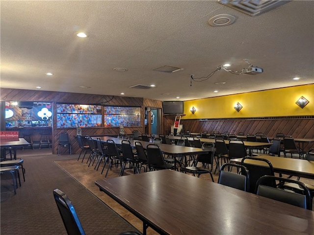 dining area featuring wood walls, carpet floors, and a textured ceiling