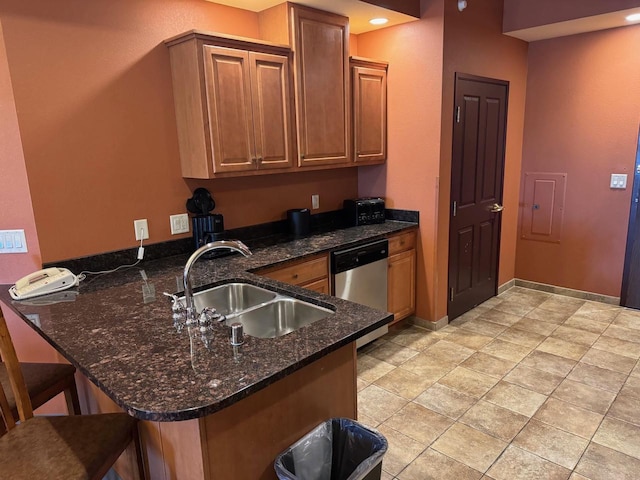 kitchen with kitchen peninsula, stainless steel dishwasher, dark stone countertops, sink, and light tile floors