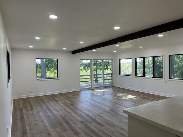 spare room with beam ceiling, a healthy amount of sunlight, and wood-type flooring