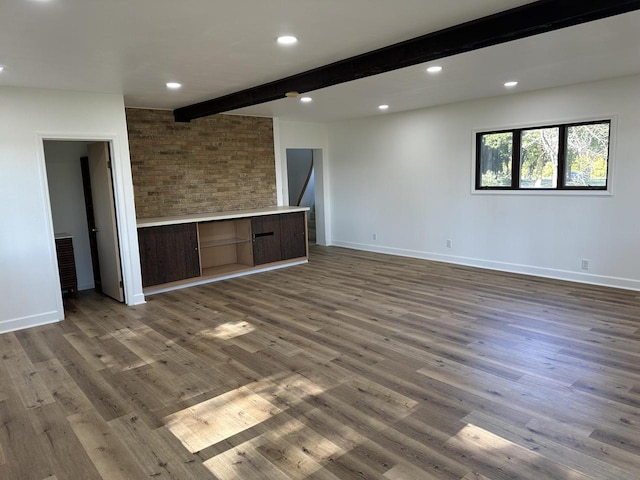 unfurnished room featuring beamed ceiling, built in desk, and dark wood-type flooring