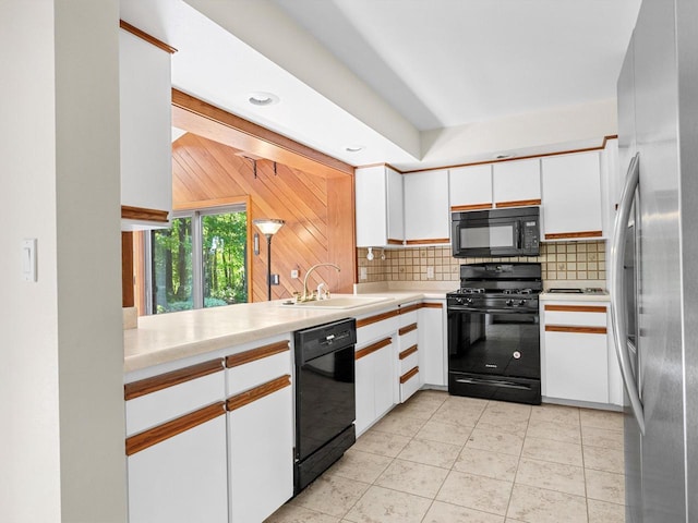 kitchen with sink, tasteful backsplash, white cabinets, light tile patterned flooring, and black appliances