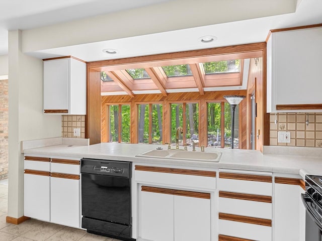 kitchen featuring dishwasher, white cabinetry, sink, and a skylight