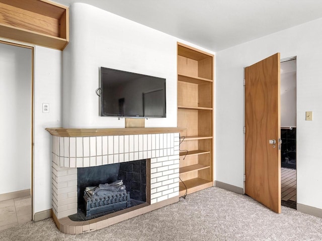 unfurnished living room featuring built in features, light colored carpet, and a brick fireplace