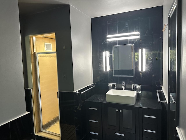 bathroom with vanity, tile walls, a shower with shower door, and backsplash