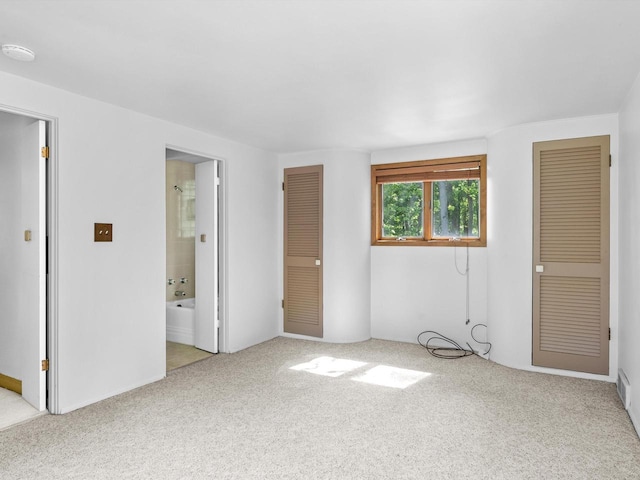 unfurnished bedroom with connected bathroom and light colored carpet