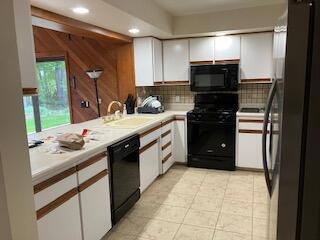 kitchen featuring tasteful backsplash, sink, white cabinets, and black appliances