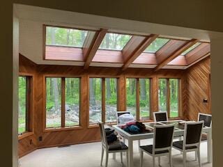 sunroom / solarium featuring coffered ceiling, plenty of natural light, beam ceiling, and a skylight