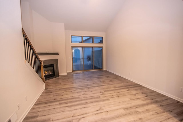 unfurnished living room featuring high vaulted ceiling and light hardwood / wood-style floors