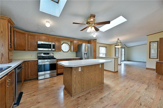 kitchen featuring a center island, light wood-type flooring, stainless steel appliances, lofted ceiling with skylight, and ceiling fan