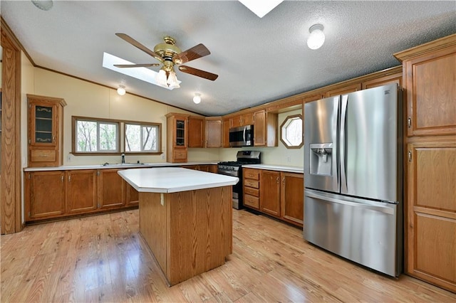 kitchen featuring appliances with stainless steel finishes, a center island, lofted ceiling with skylight, and light wood-type flooring