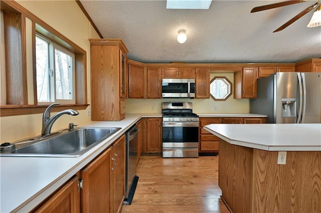 kitchen featuring ceiling fan, light hardwood / wood-style floors, stainless steel appliances, a textured ceiling, and sink