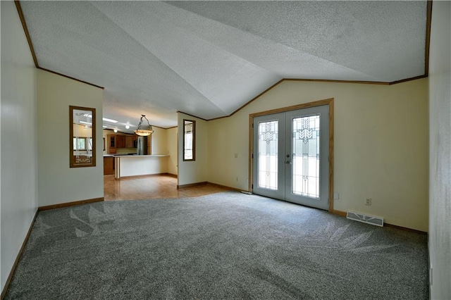 carpeted empty room featuring french doors, a textured ceiling, and vaulted ceiling