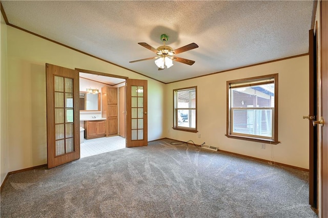 carpeted empty room with ceiling fan, ornamental molding, french doors, a textured ceiling, and lofted ceiling