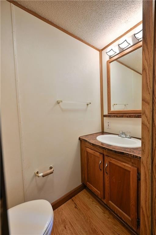 bathroom with hardwood / wood-style flooring, vanity, toilet, and a textured ceiling