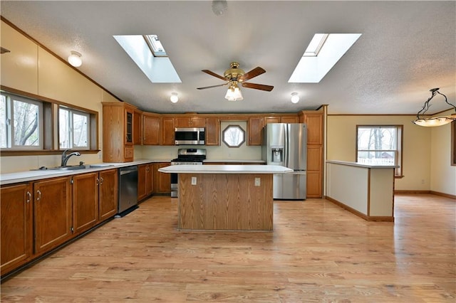 kitchen featuring a kitchen island, ceiling fan, light wood-type flooring, and appliances with stainless steel finishes