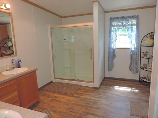 bathroom with wood-type flooring, an enclosed shower, oversized vanity, and crown molding