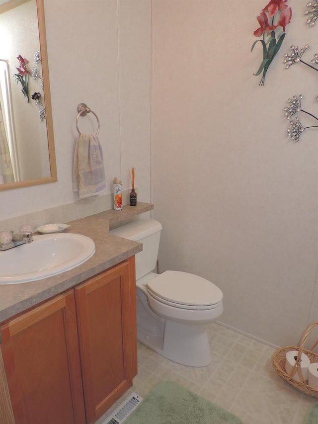 bathroom featuring tile flooring, vanity, and toilet