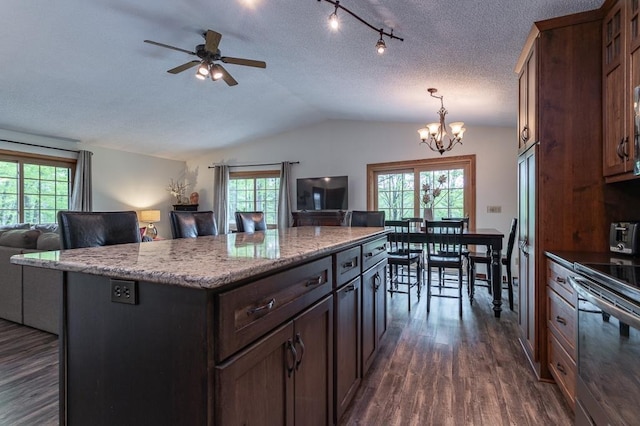 kitchen with dark wood-type flooring, vaulted ceiling, hanging light fixtures, a kitchen island, and stainless steel electric stove