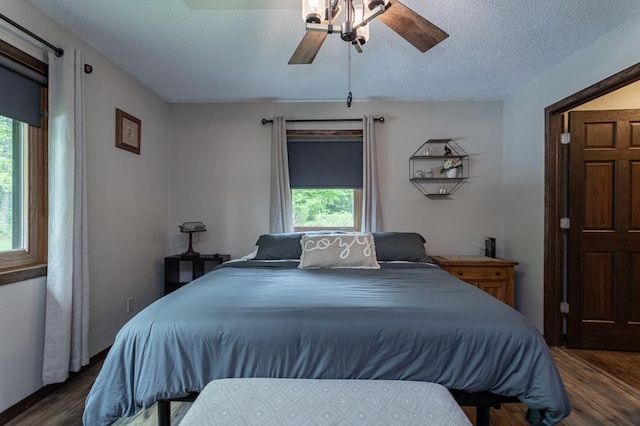 bedroom with ceiling fan, dark hardwood / wood-style floors, and a textured ceiling