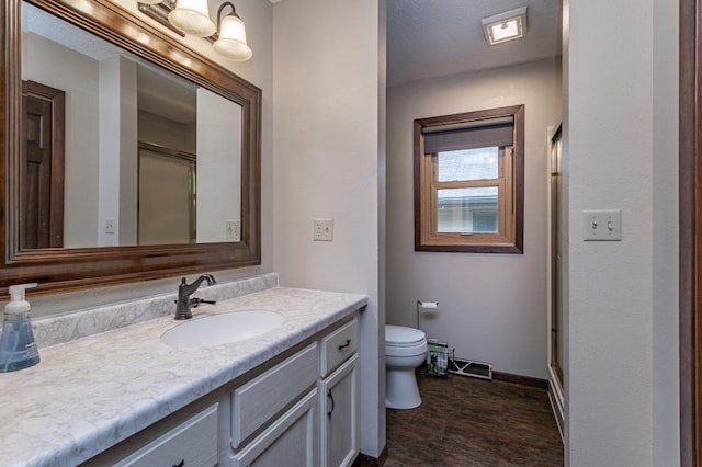 bathroom with vanity, a shower with door, and toilet