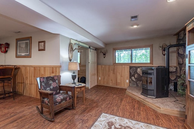 basement featuring dark wood-type flooring, wood walls, and a wood stove