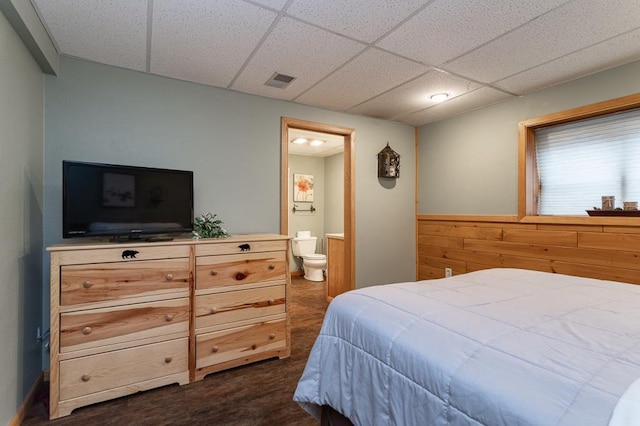 bedroom with wooden walls, a paneled ceiling, and ensuite bath