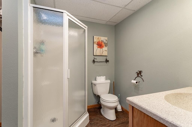 bathroom featuring a paneled ceiling, toilet, an enclosed shower, and sink